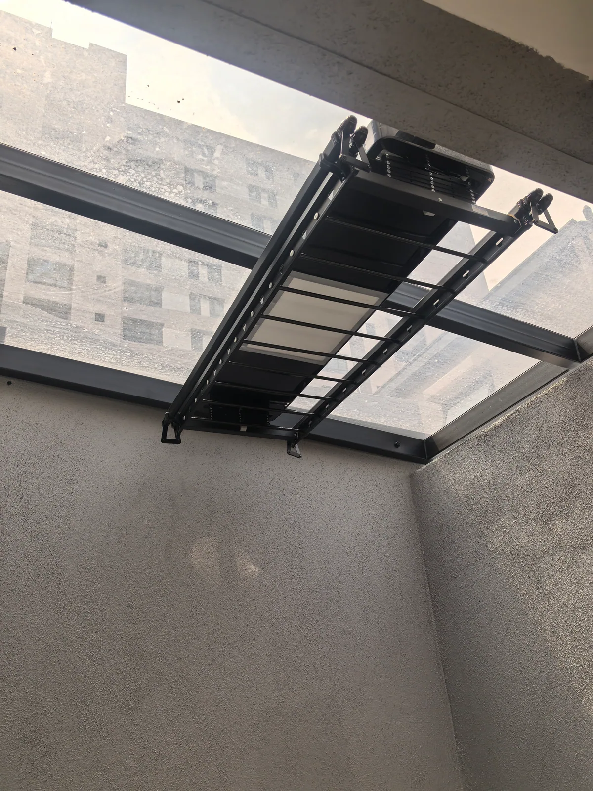 Manual lifting clothes drying rack installed on metal roof support beams