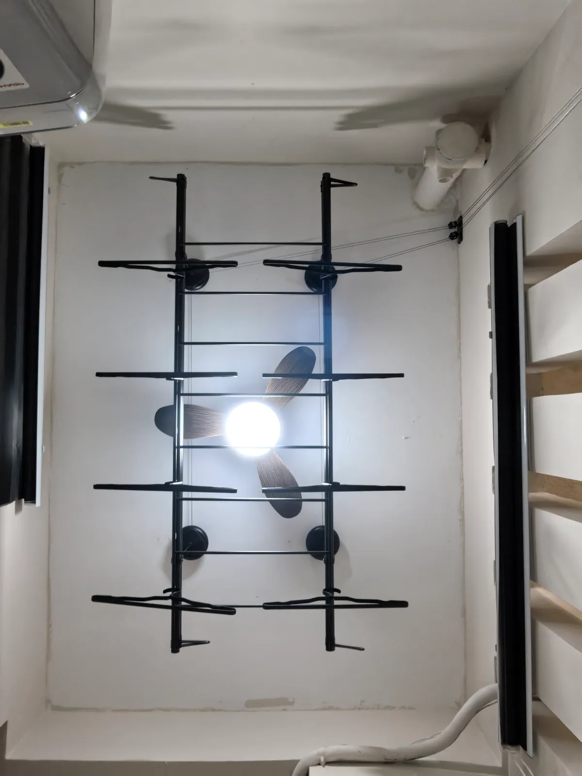 Manual lifting clothes drying rack positioned around a ceiling fan
