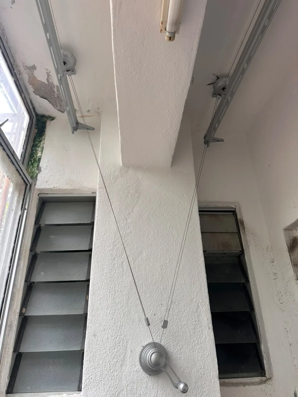 Manual clothes drying rack with mounting points at different ceiling levels