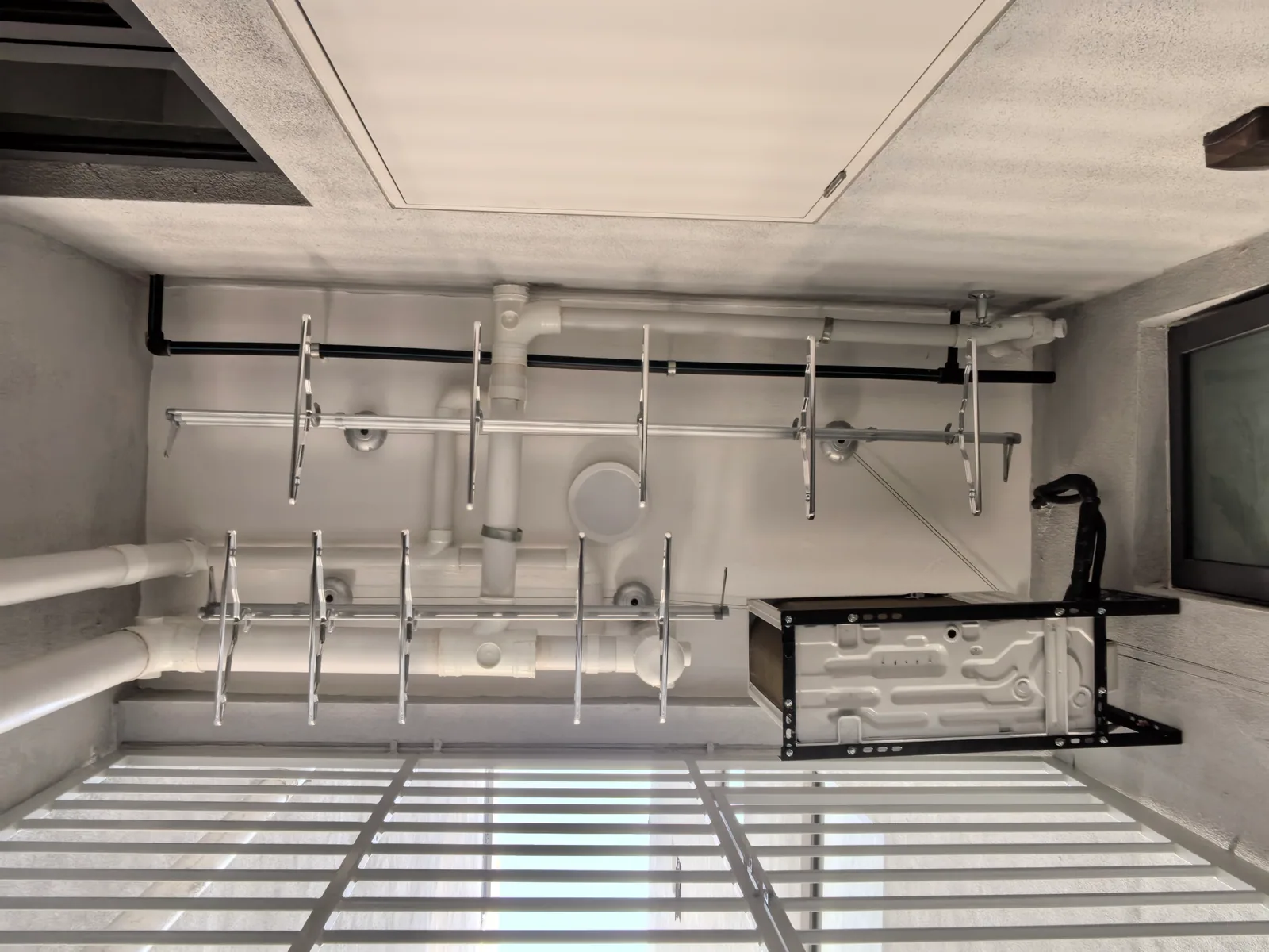 Clothes drying rack installed under water pipes with different rod lengths to suit the site